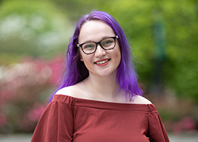 female student with glasses and purple hair on campus