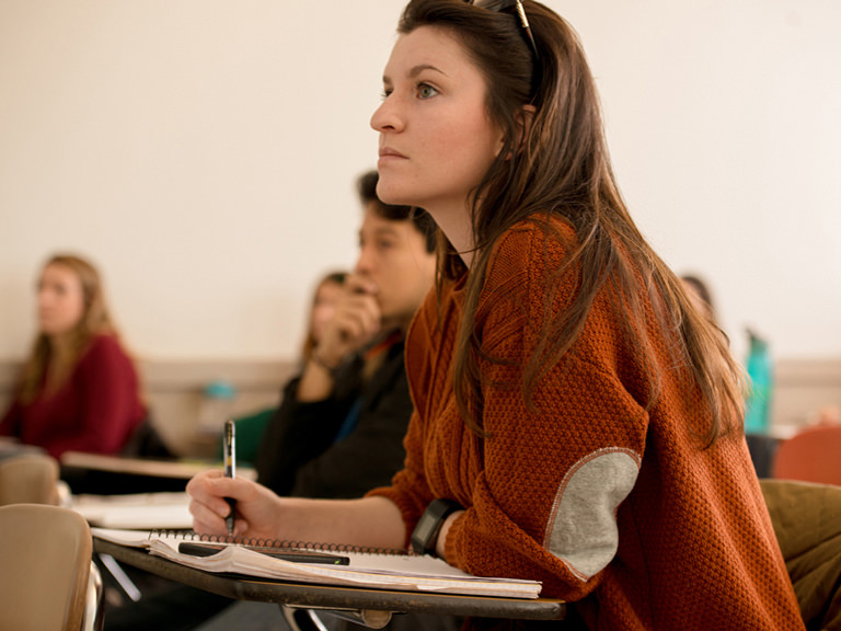 image of female student avidly watching classroom lecture