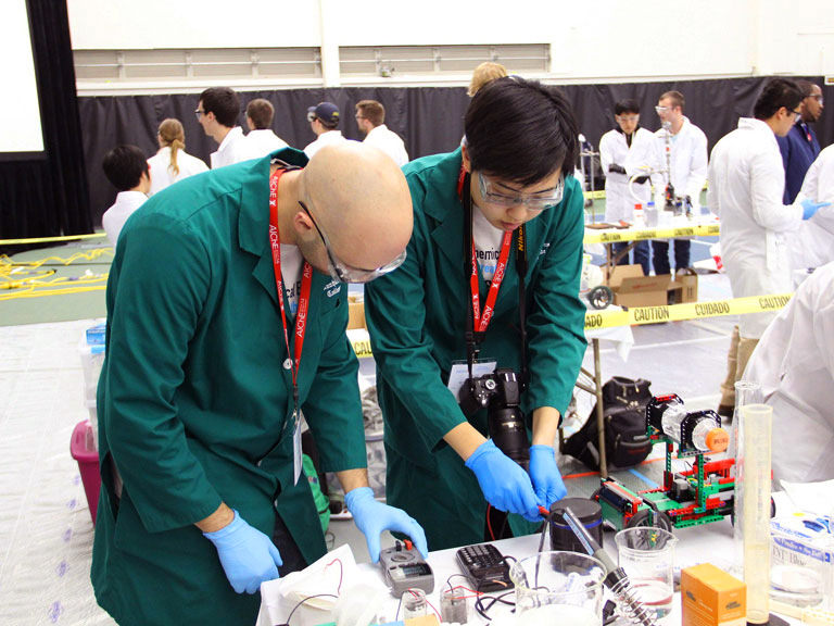 Two students get their hands dirty working on a chemical engineering project.
