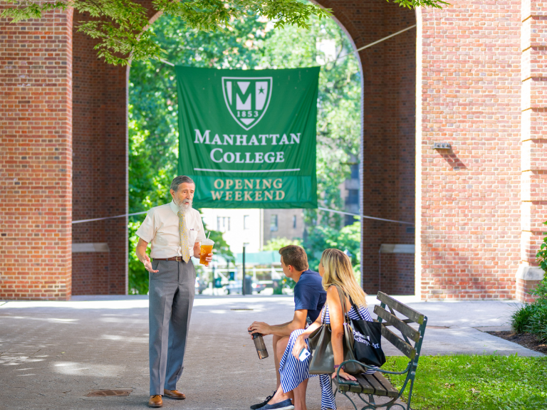 Professor talking to two students with the Opening Weekend Sign