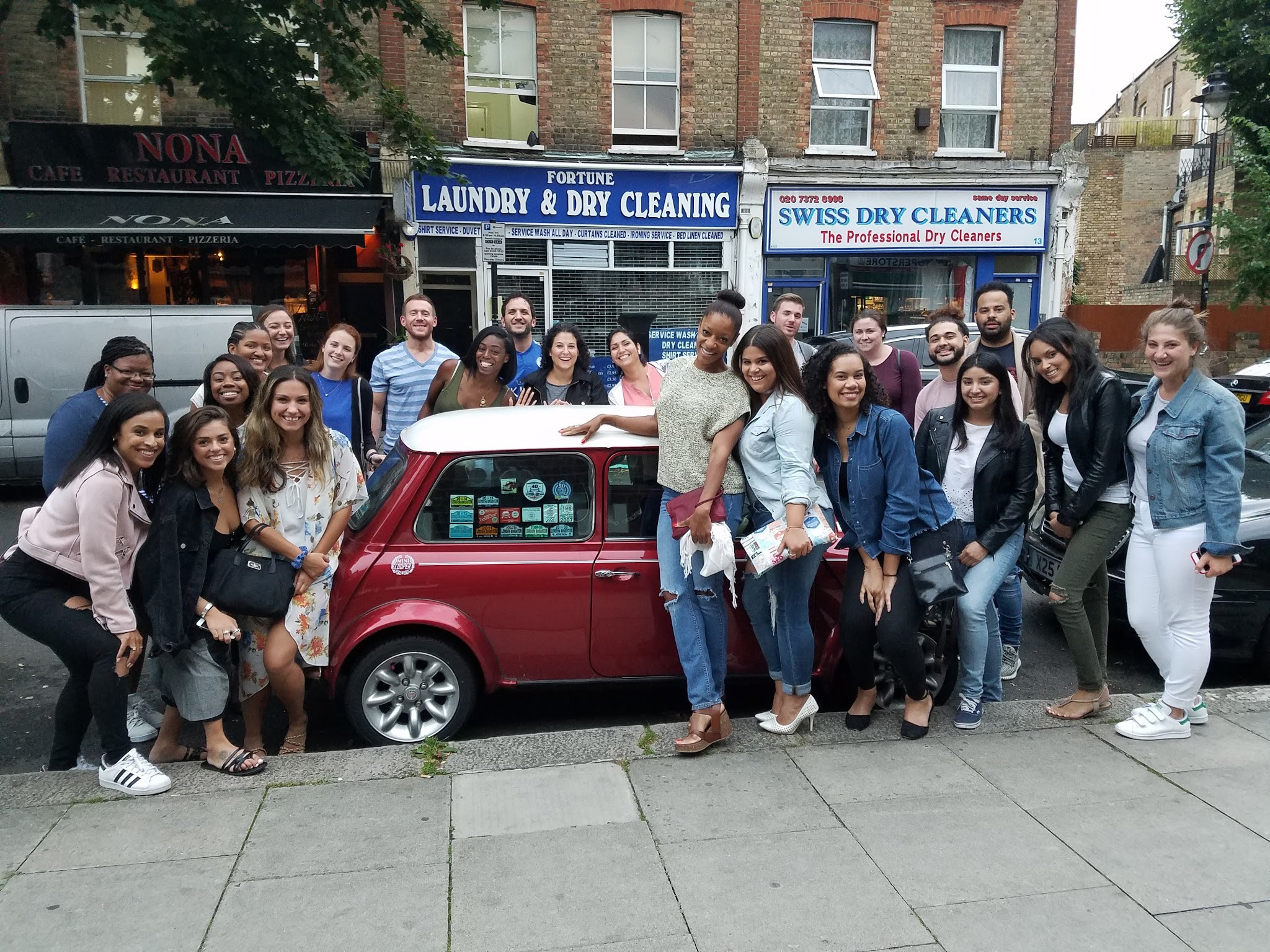 students pose around a mini cooper car in london