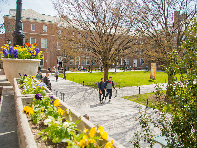 the quadrangle on a sunny day with brightly colored flower boxes and students walking around