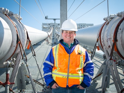 alum Amanda Rogers poses on bridge in construction hat