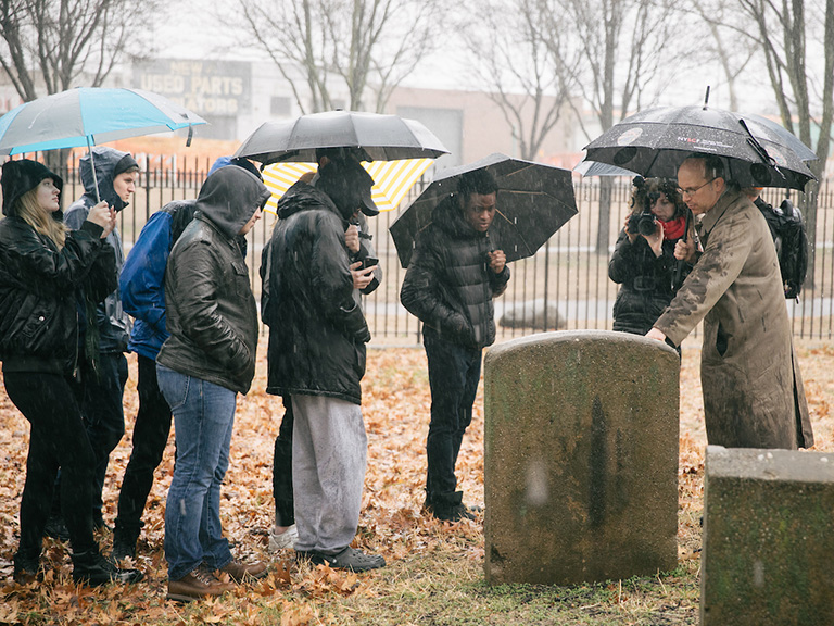 Adam Arenson points to headstone in Hunts Point's Drake Park