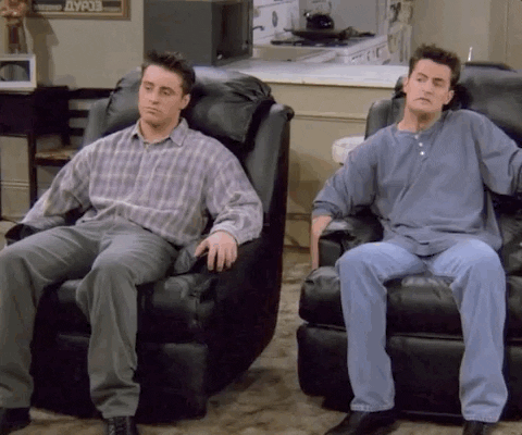 two men lean back in reclining living room chairs