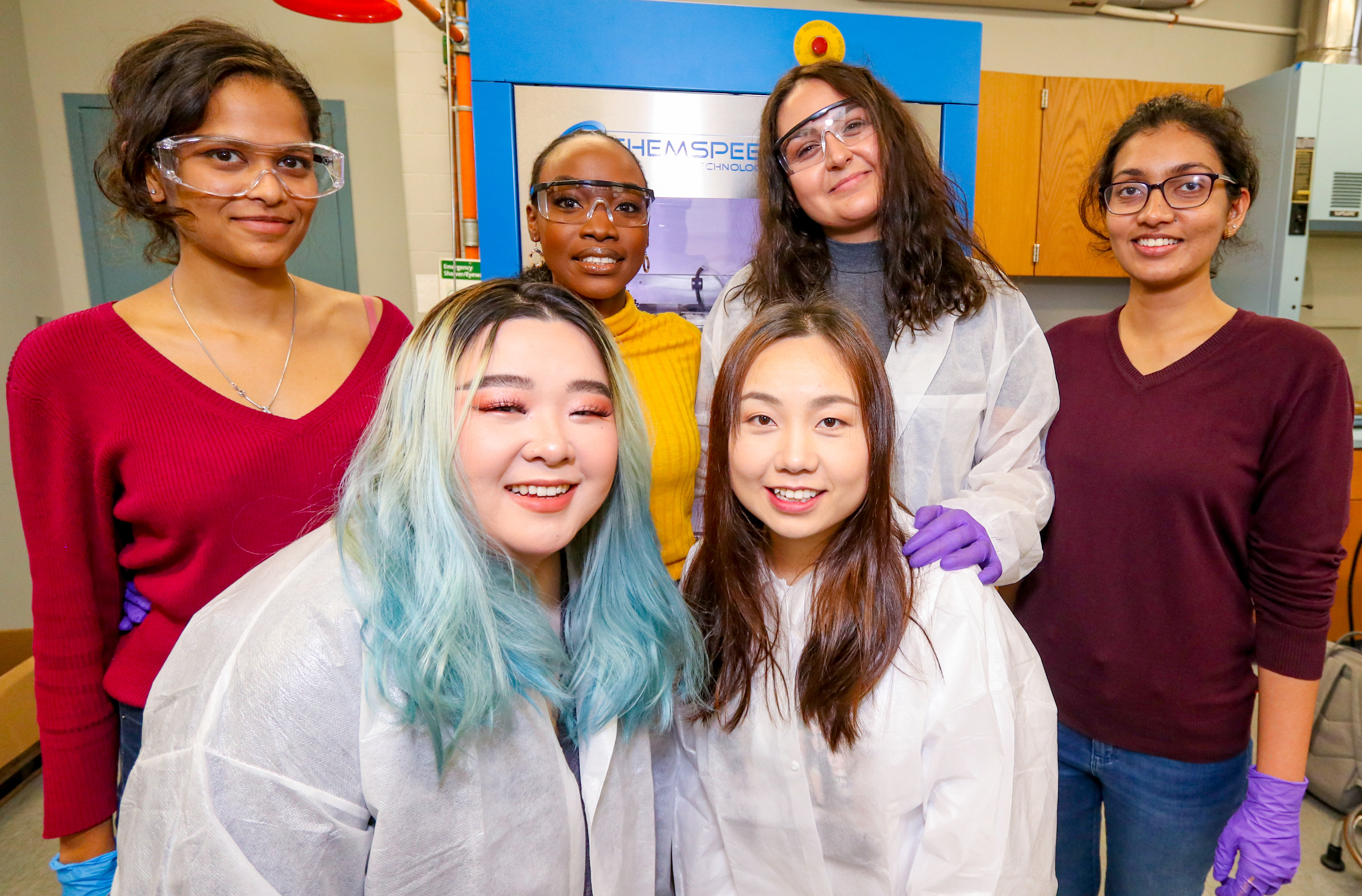 Six graduate students smiling in the cosmetic engineering lab at Manhattan College.
