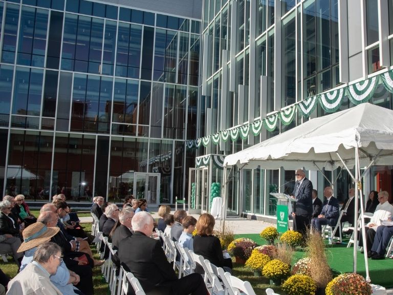 man speaking to crowd of people at higgins building dedication event