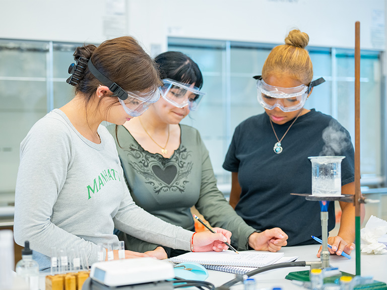 photo of the 3 female manhattan university students in the chemical engineering lab