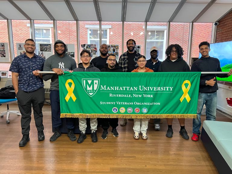 Photo of Manhattan University Student Veterans In the Veterans Success Center holding a Manhattan University banner