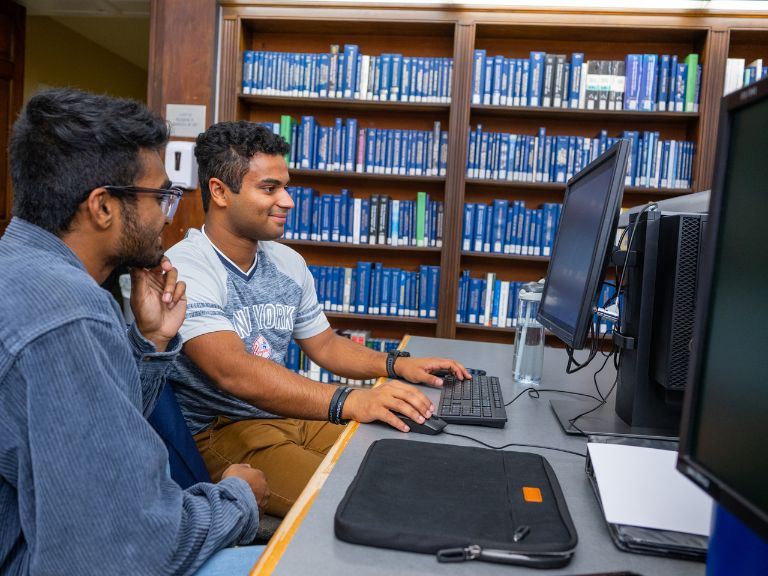 two students in the library sitting at a computer