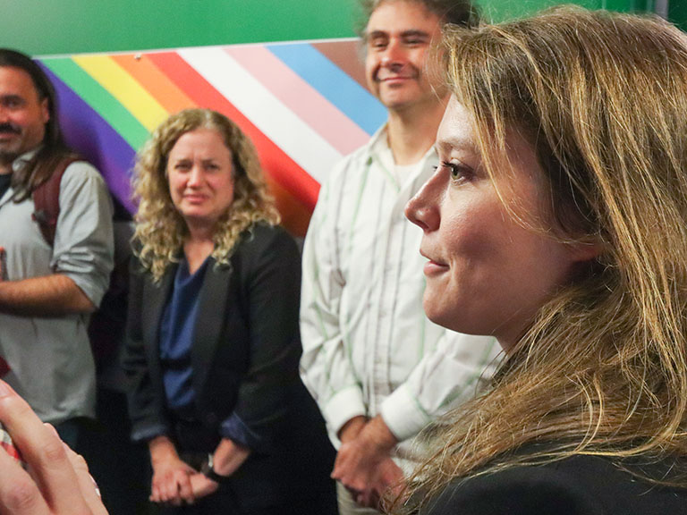 A group of people standing in front of a rainbow colored wall